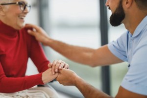 Φροντιστής κρατά τα χέρια μιας ηλικιωμένης γυναίκας