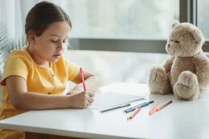 Κορίτσι ζωγραφίζει δίπλα σε ένα αρκουδάκι