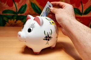 Κουμπαράς και κέρματα πάνω σε ξύλινο τραπέζι
