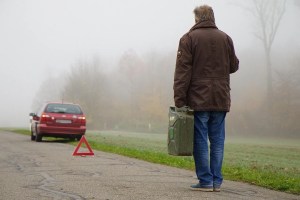 Οδηγός με τρίγωνο ασφαλείας πίσω από το ακινητοποιημένο αυτοκίνητό του