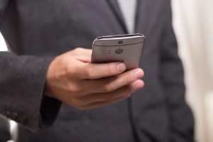 Άντρας με σακάκι κοιτάζει το κινητό του