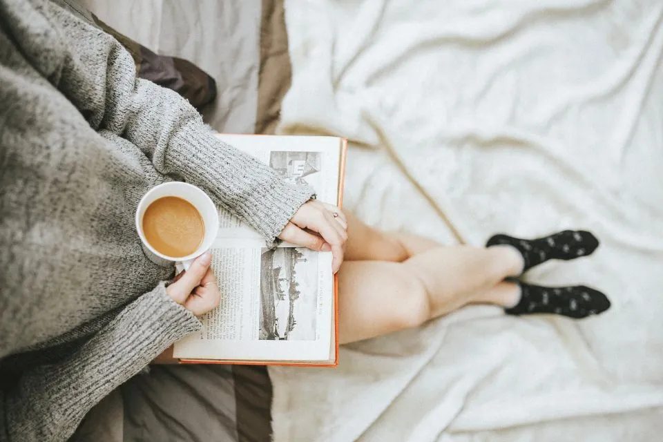Женщина читает книгу с чашкой кофе