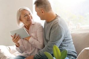 Ζευγάρι μεγαλύτερης ηλικίας κοιτάζει μαζί ένα tablet στον καναπέ