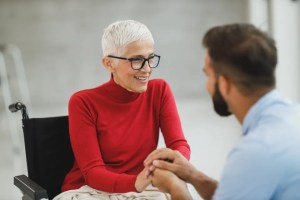 Ηλικιωμένη γυναίκα σε αναπηρικό αμαξίδιο με τον φροντιστή της