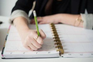 Χέρι γράφει σε ανοιχτό σημειωματάριο