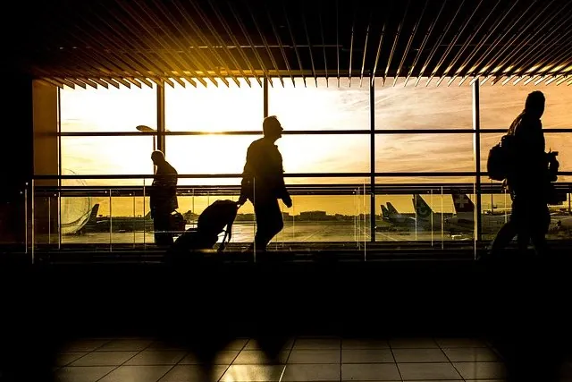 Travellers with luggage at the airport at dusk
