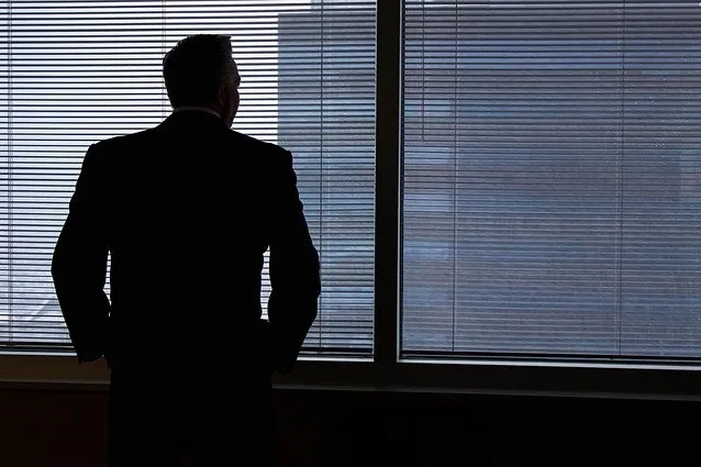 Άντρας κοιτάζει σκεφτικός έξω από το παράθυρο